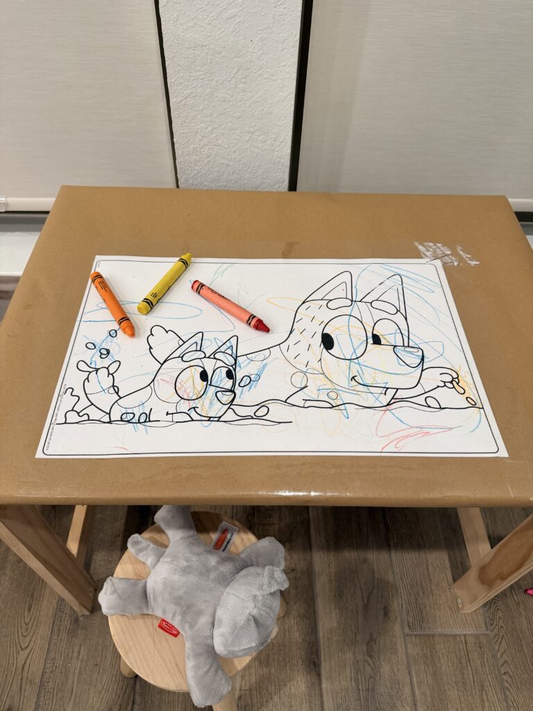 Crayons and paper set up on a toddler table