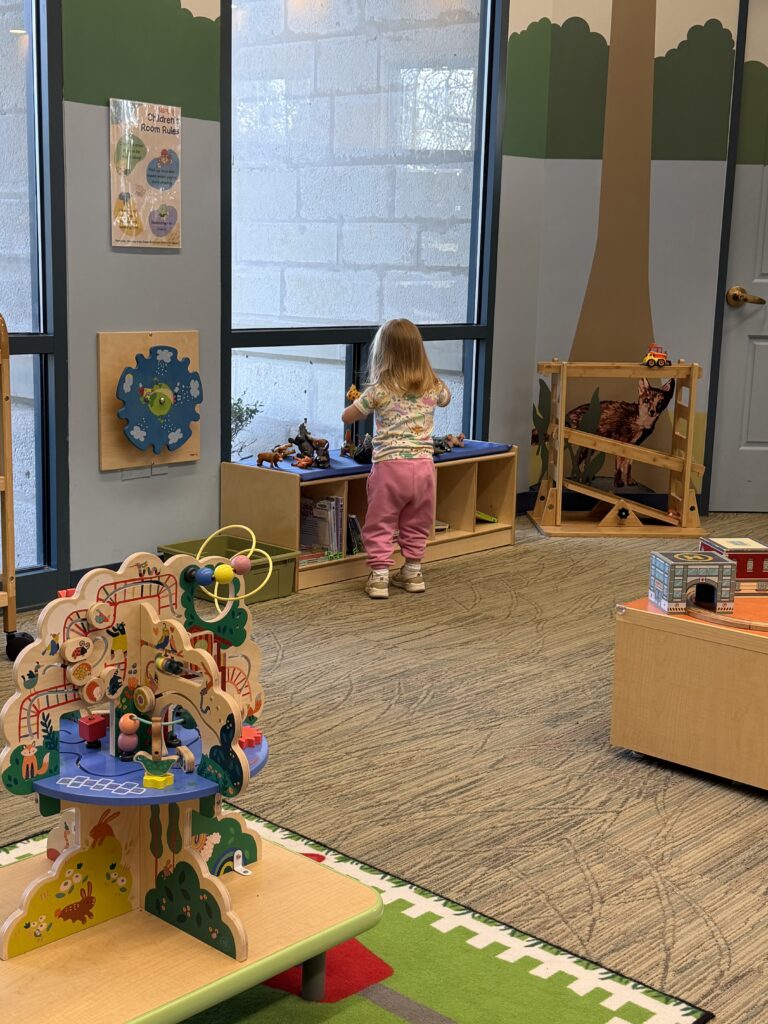 Toddler playing with toys in the children’s section of the library.